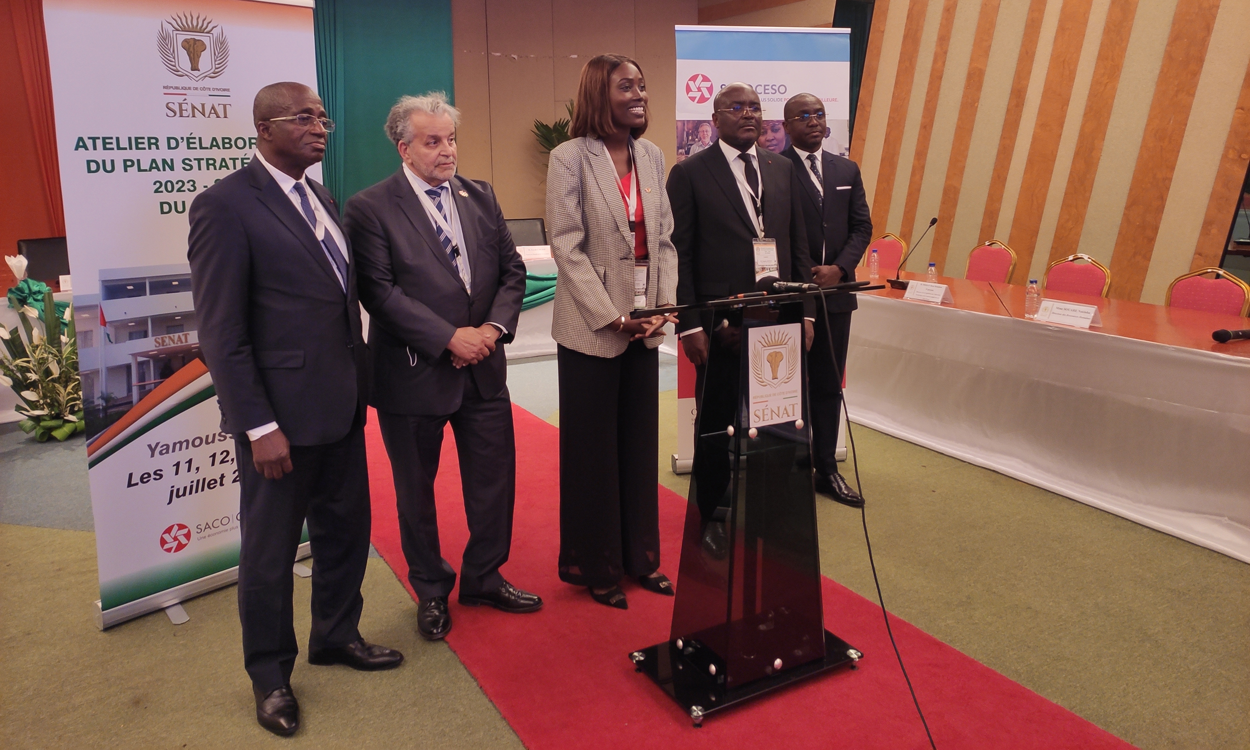 Members of the senate in Ivory Coast stand around a podium