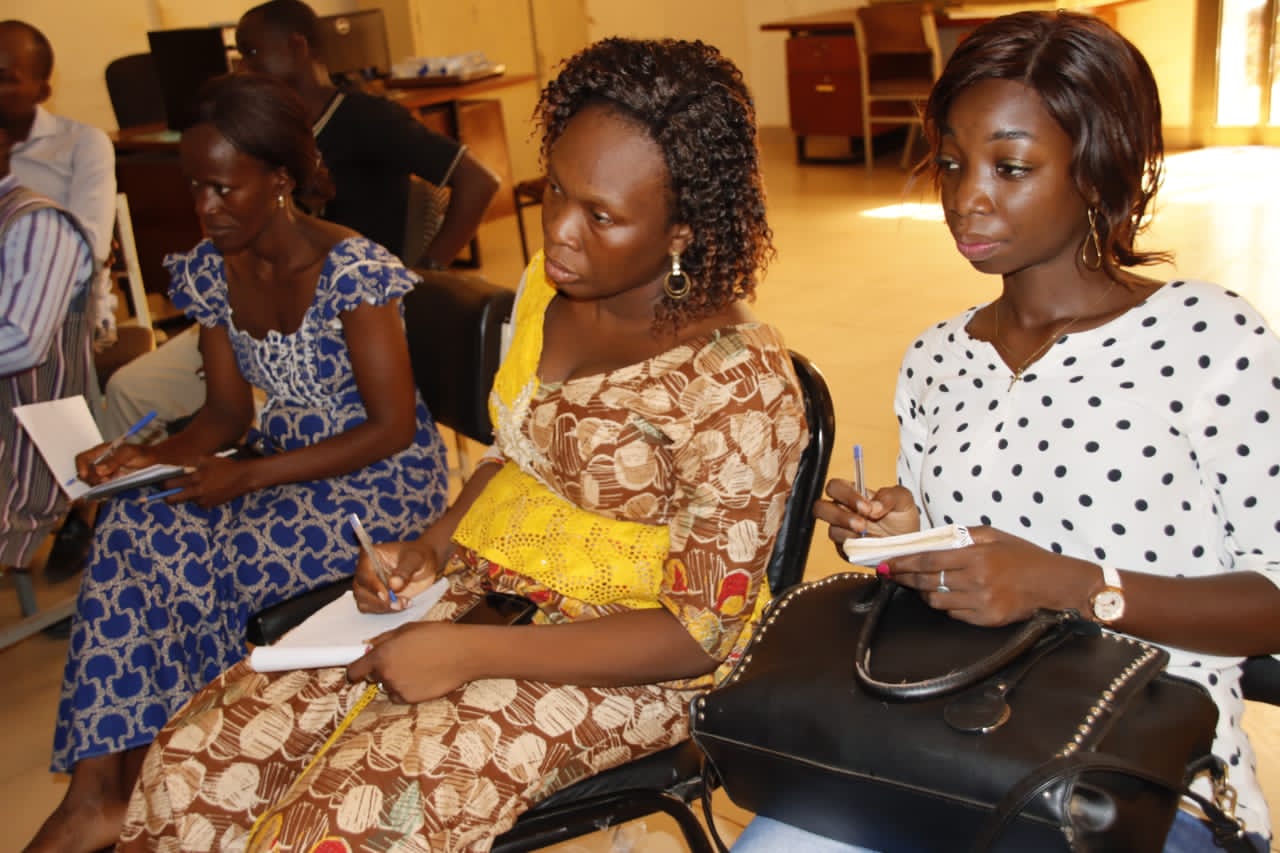 Three seated women in Burkina Faso take notes
