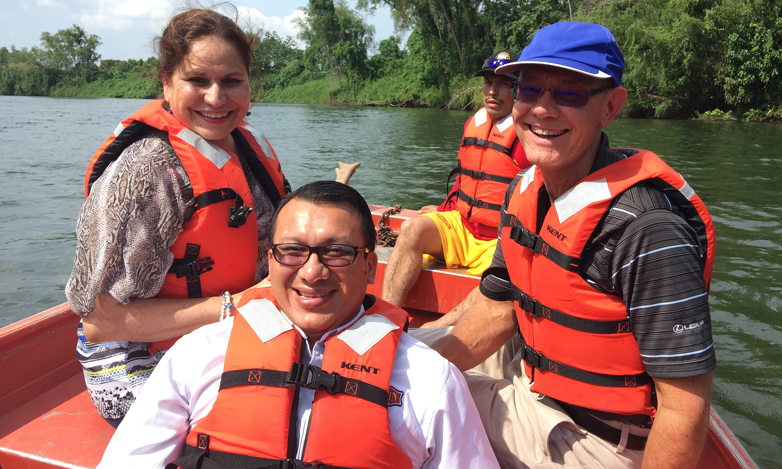 Four people wear life jackets in a small boat