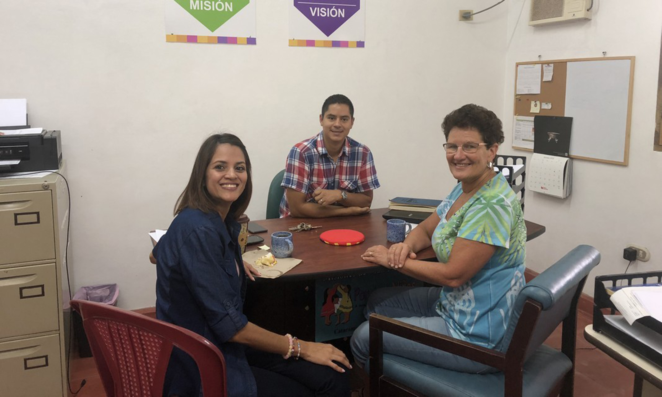 Three people seated at a desk in an office
