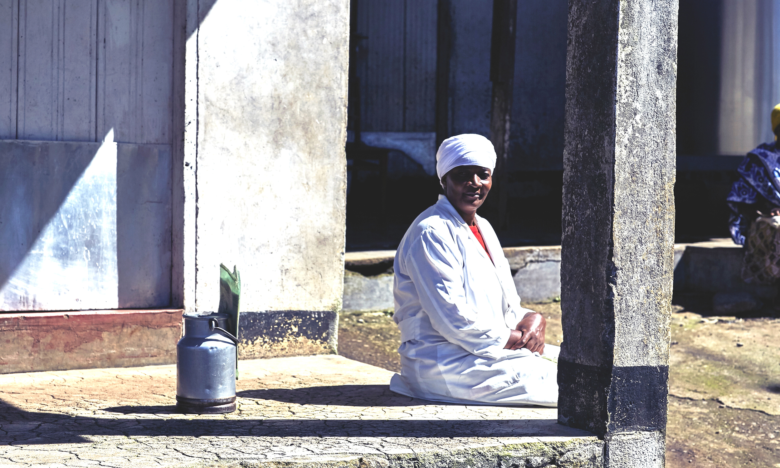 A woman sits in the sun on a stoop
